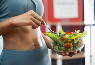 Effective Ways To Keep Your Stomach Healthy Close up of a sport woman with her sexy belly, she holding a bowl of fresh healthy food