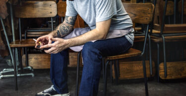 How High-Functioning Addiction Hides in Successful Men Man sitting using mobile phone on the chair
